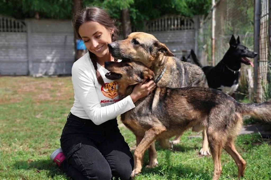 Integrante da equipe junto de cães em uma área externa